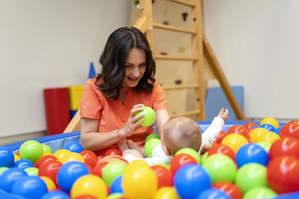 Terapeuta juega con un bebé en una piscina de bolas de colores