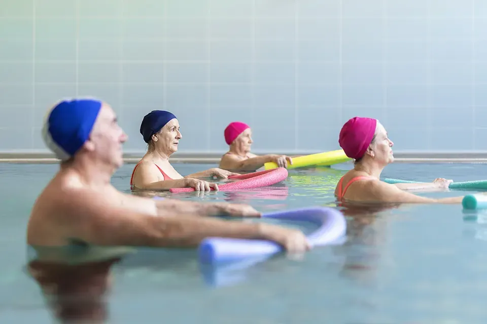 Pacientes con gorro de baño hacen ejercicios en la piscina terapéutica